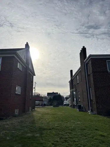 Sunlight pierces through the clouds, framed by suburban homes.